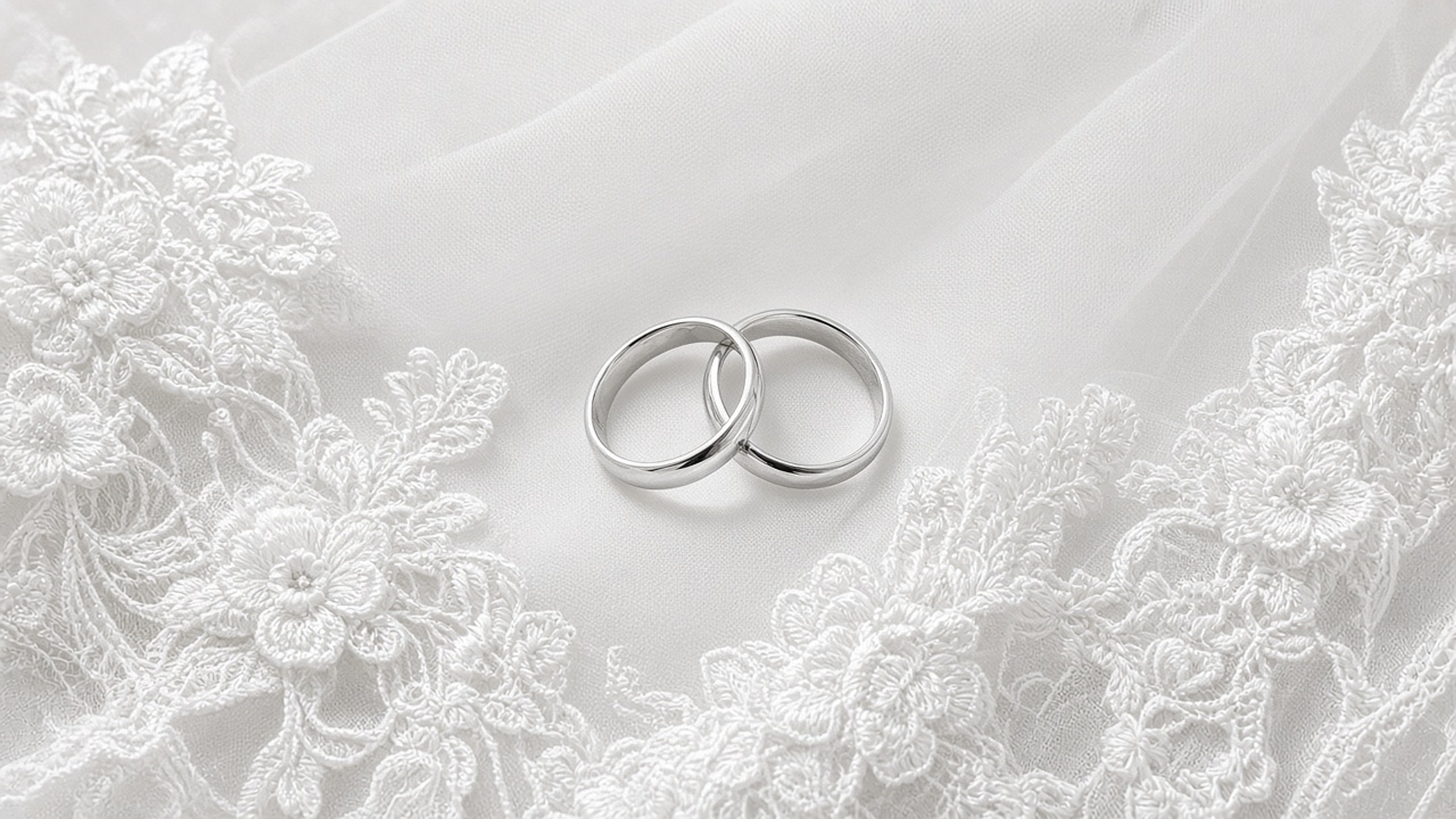 Two wedding bands resting together on a lace veil